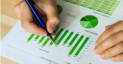 Person holding pen above statistics document.