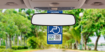 Disabled Person Parking Placard hanging from rearview mirror of a car.